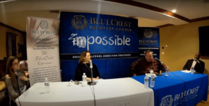 BlueCrest Health Group employees sit at a table with microphones to deliver a podcast