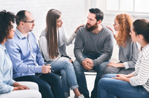a circle of people in a group therapy program listens to someone share their story