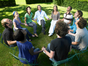 a group in a holistic therapy program meditates in a circle outdoors