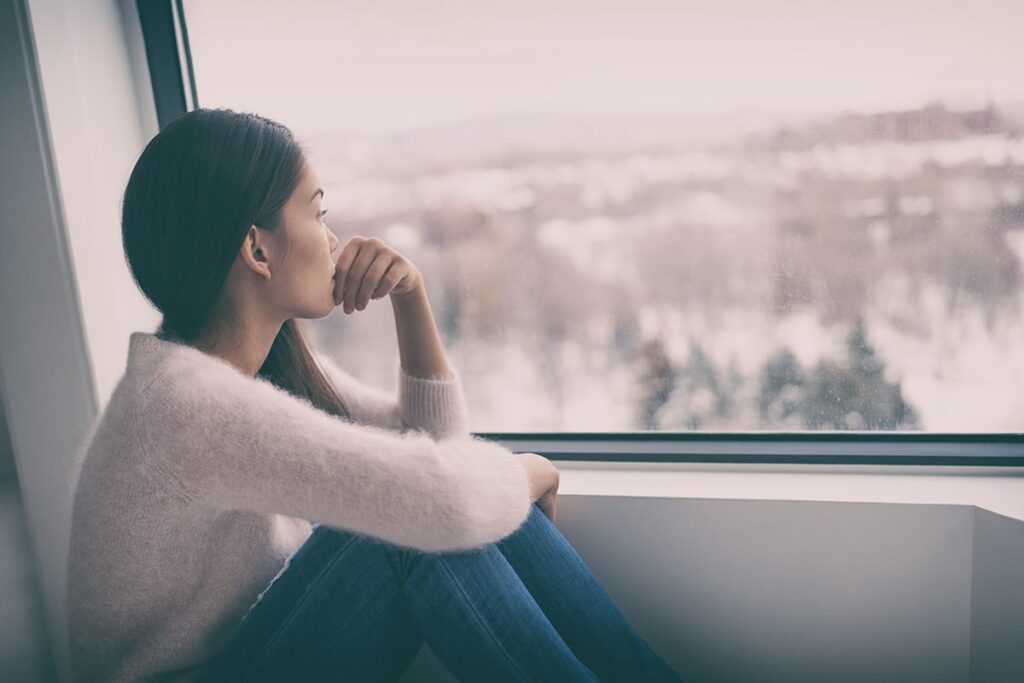 a person living with seasonal depression looks sadly out of a window