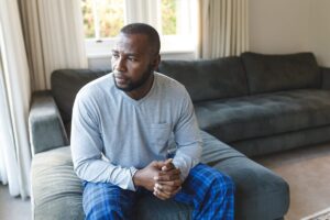 a person with symptoms of anxiety sits on a couch nervously