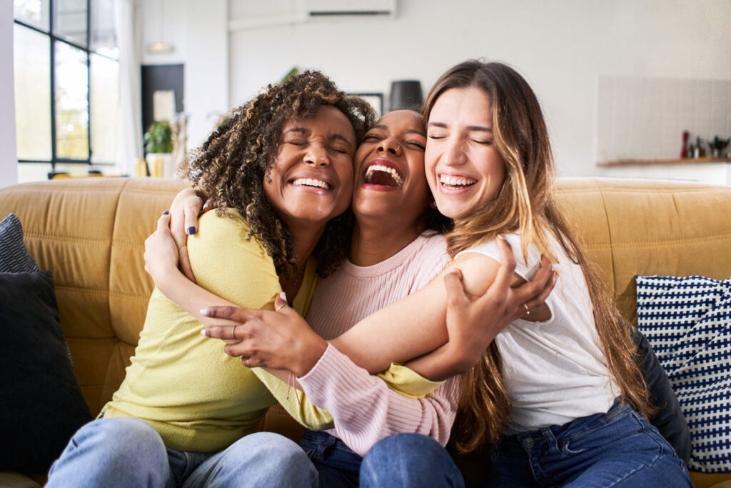 Three happy friends hugging smiling after one of them stops drinking alcohol