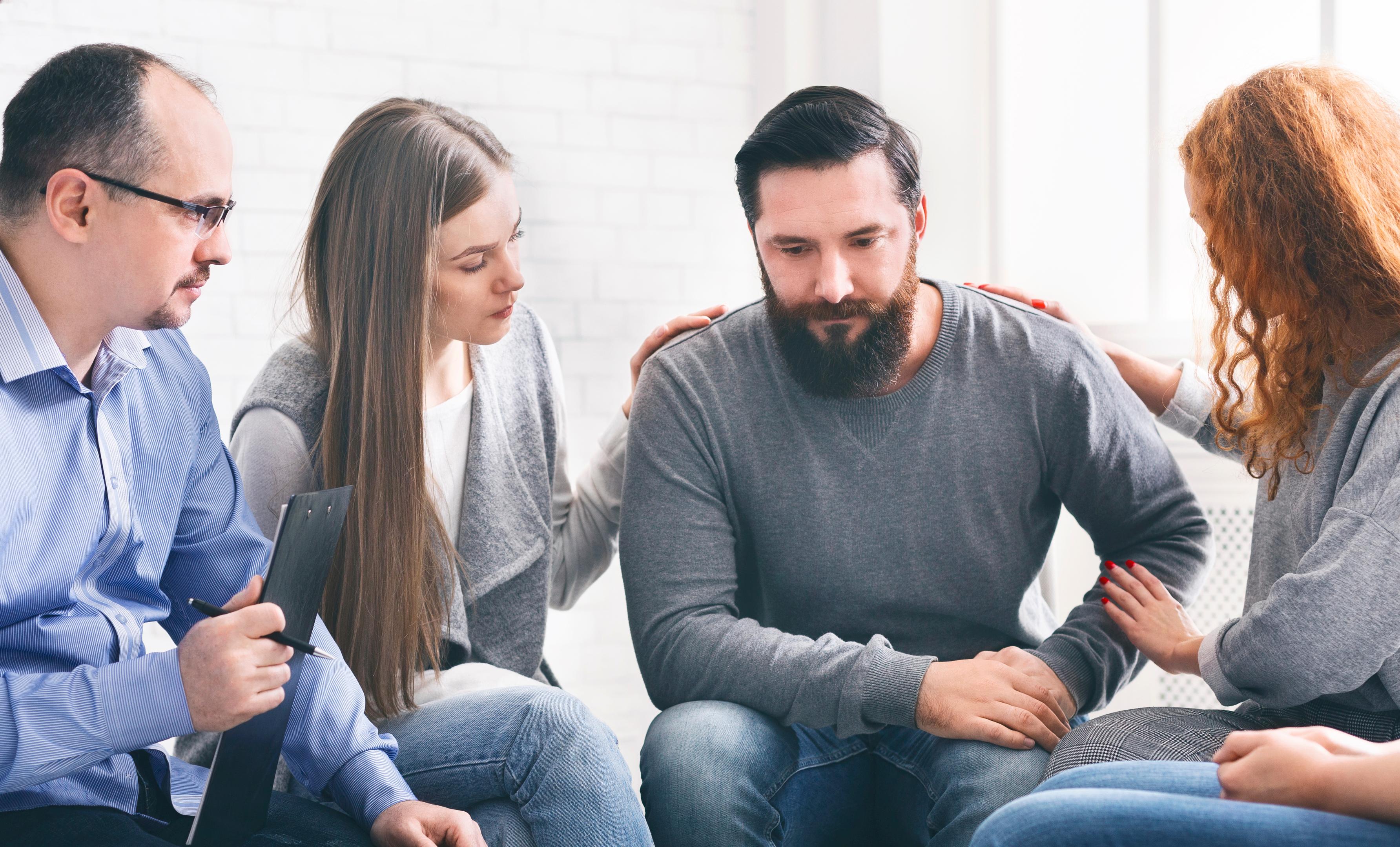A man receives support in therapy, answering the question, how long is alcohol rehab