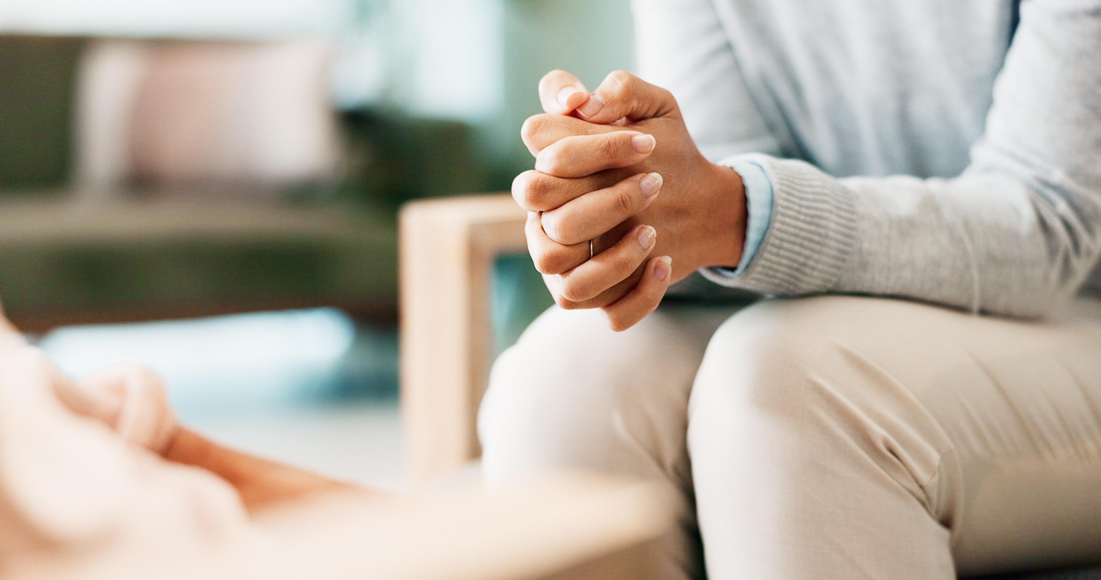 Focus on clasped hands in a dual diagnosis therapy session